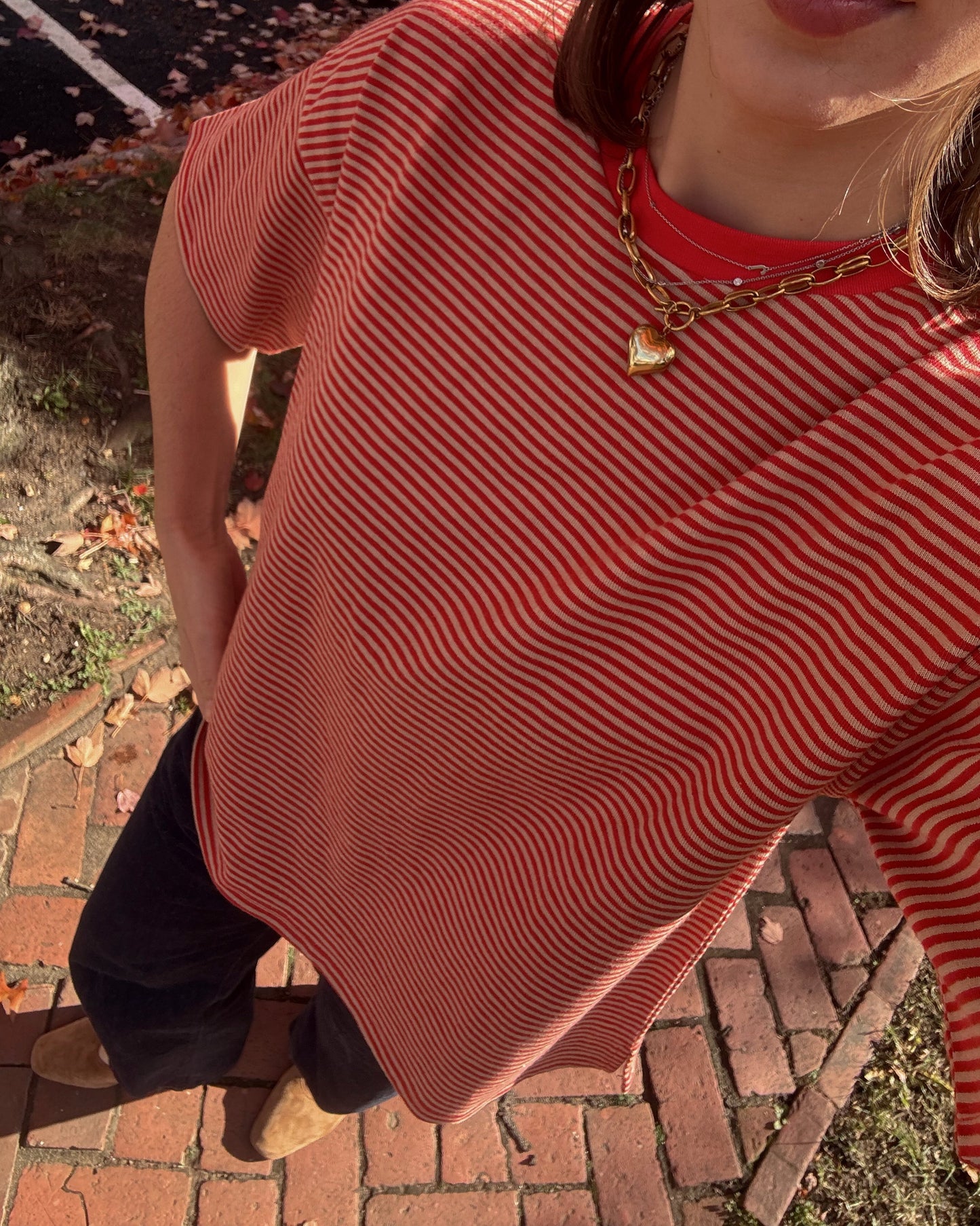 Person wearing a red and white striped shirt on a brick sidewalk.